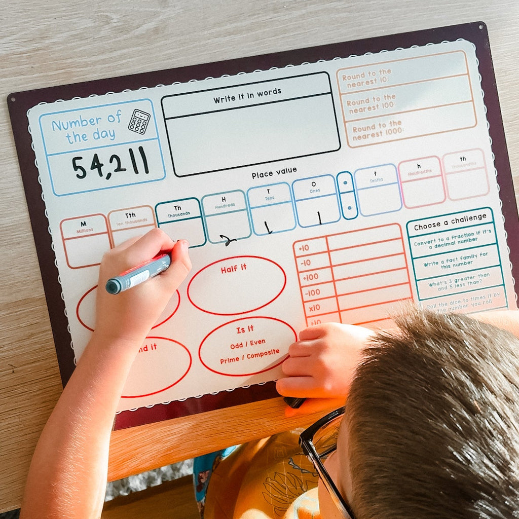 Child writing on a dry erase board with educational content