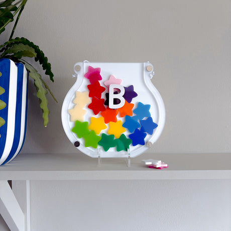 Colorful letter 'B' toy on a white shelf with a plant in the background